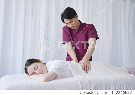 Female masseuse giving back massage Female masseuse giving back massage 132240657