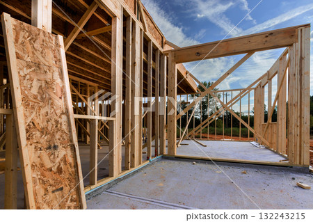 New home construction progresses with wooden frames beams erected in peaceful neighborhood. New home construction progresses with wooden frames beams erected in peaceful neighborhood. 132243215