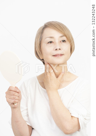 Senior woman with gray hair holding a hand mirror 132243248