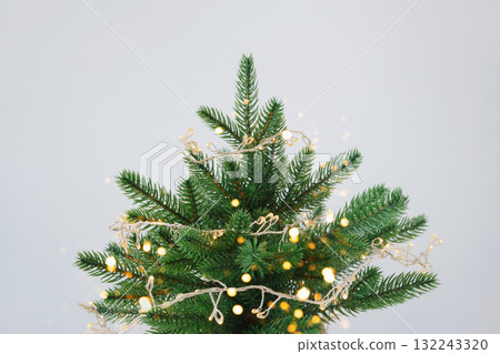 Festive christmas tree with twinkling lights against white background Close-up 132243320