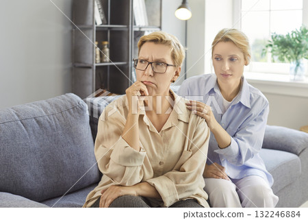 Concerned elderly woman receiving gentle support from caregiver at home today 132246884