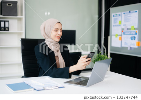 Young Muslim woman working with laptop and tablet Young Muslim woman working with laptop and tablet 132247744