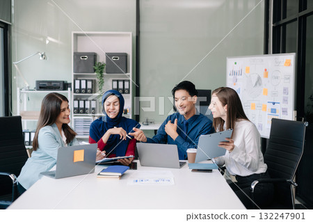 Happy businesspeople while collaborating on a new project in an office. Group of diverse businesspeople using a laptop and tablet 132247901