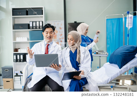 Medical professionals in modern hospital collaborating on patient care, research, and diagnosis. Doctors and nurses in hijabs discussing treatment plans, lab 132248181