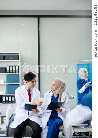 Medical professionals in modern hospital collaborating on patient care, research, and diagnosis. Doctors and nurses in hijabs discussing treatment plans, lab 132248182