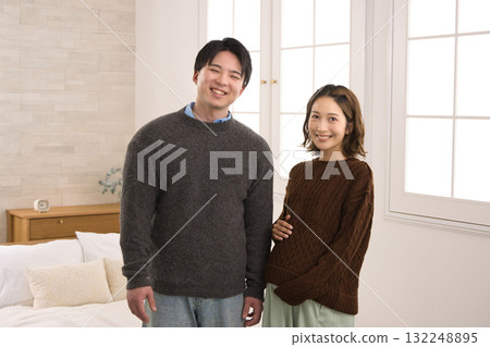 A young couple standing by the window, a pregnant woman 132248895