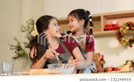Family Cooking Happy mother and daughter enjoying baking together in a festive kitchen. 132249459