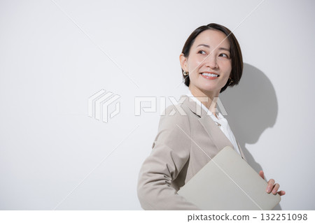 A woman looking back with a laptop, smiling saleswoman, career woman 132251098