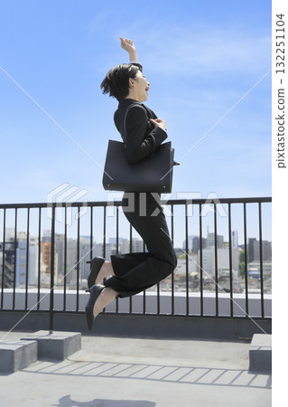 一位身著西裝的女商人在藍天下跳躍 一位身著西裝的女商人在藍天下跳躍 132251104
