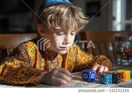 A charming boy in a Jewish yarmulke plays at the table. 132251193
