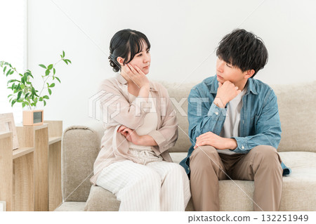 A young Asian couple discussing their worries while sitting on the sofa in the living room 132251949