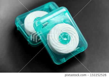 Dental floss in green plastic cases on black ceramic close up Dental floss in green plastic cases on black ceramic close up 132252526
