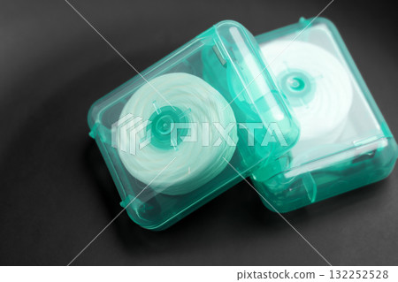 Dental floss on a black surface. Oral hygiene products close up Dental floss on a black surface. Oral hygiene products close up 132252528