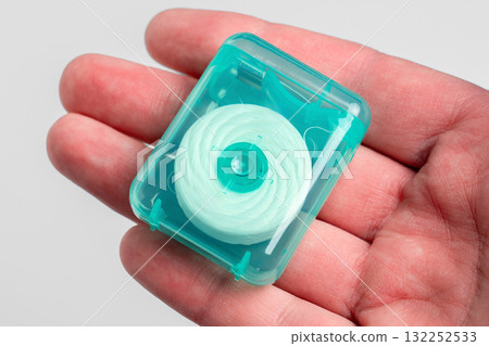 Dental floss in a green plastic case on the palm of hand. Oral hygiene products Dental floss in a green plastic case on the palm of hand. Oral hygiene products 132252533