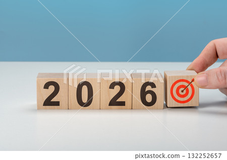 Male hand putting last wooden block with dartboard symbol to complete 2026 number for new year business goal concept 132252657