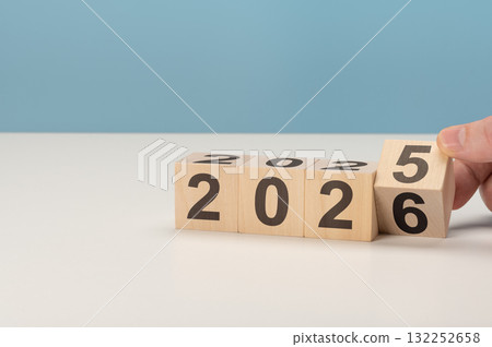 Hand flipping wooden block to change year from 2025 to 2026. Concept of new year's eve and starting fresh Hand flipping wooden block to change year from 2025 to 2026. Concept of new year's eve and starting fresh 132252658