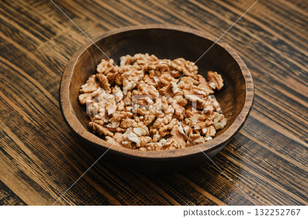 Bowl filled with shelled walnut pieces on a wooden table in a cozy kitchen setting 132252767