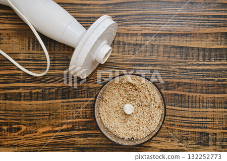 Kitchen preparation with a food processor and finely ground ingredients on wooden countertop 132252773