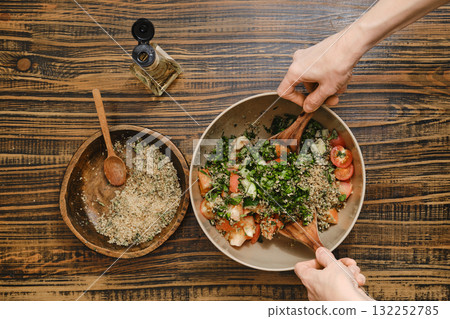 Making a fresh salad with tomatoes and herbs on a rustic wooden table in the kitchen Making a fresh salad with tomatoes and herbs on a rustic wooden table in the kitchen 132252785