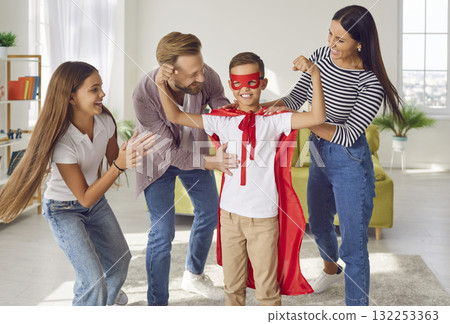 Funny Superhero boy shows his strength while having fun with his family at home. Funny Superhero boy shows his strength while having fun with his family at home. 132253363