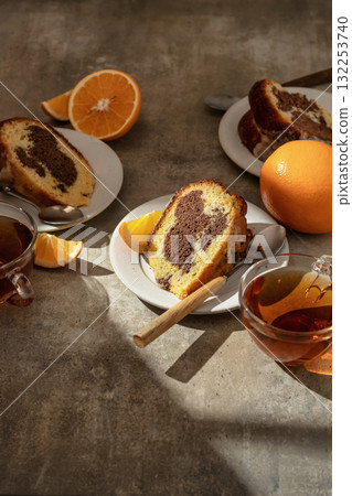 Piece of orange and chocolate marble bundt cake in bright morning light with clear shadows. Fruity citrus dessert on green textured background Piece of orange and chocolate marble bundt cake in bright morning light with clear shadows. Fruity citrus dessert on green textured background 132253740