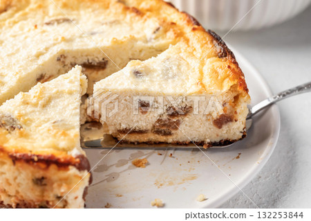 Homemade cottage cheese casserole pie with raisins close up. Baked cheesecake for healthy breakfast on white table background Homemade cottage cheese casserole pie with raisins close up. Baked cheesecake for healthy breakfast on white table background 132253844