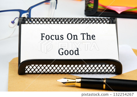 A desk adorned with stationery reflects a motivational message promoting positivity. Surrounding the sign are colorful papers and a stylish pen, inspiring creativity and focus 132254267
