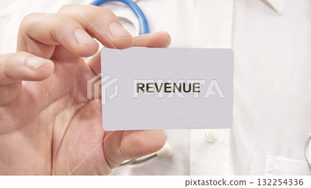A person holds a card with the word revenue prominently displayed, set against a backdrop of healthcare tools, capturing the essence of financial discussions in medical environments A person holds a card with the word revenue prominently displayed, set against a backdrop of healthcare tools, capturing the essence of financial discussions in medical environments 132254336