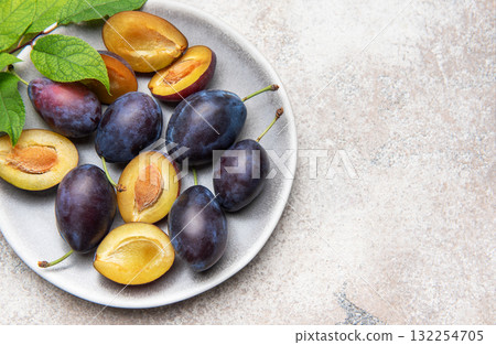 Fresh plums on plate showing halved fruit composition Fresh plums on plate showing halved fruit composition 132254705