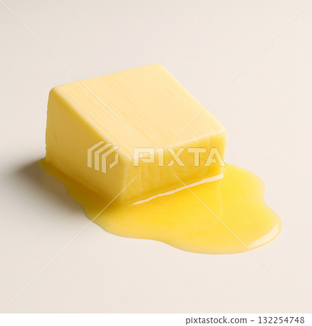 Melting butter cube tilted gently with golden liquid spreading 132254748