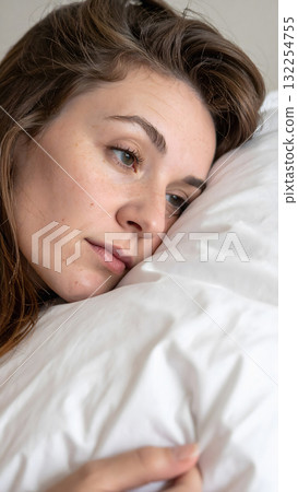 Young woman resting sideways on pillow with thoughtful look 132254755