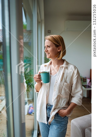 Woman enjoys a quiet morning with a warm drink Woman enjoys a quiet morning with a warm drink 132255016