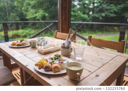 Breakfast served on wooden table in outdoor patio with forest view 132255760