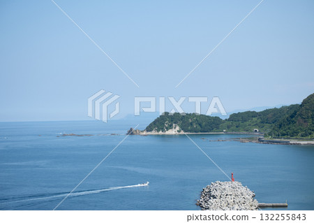 Boat cruising on calm sea near rocky coastline with lighthouse and forest Cape Ogon, Shakotan, Hokkaido, Japan 132255843