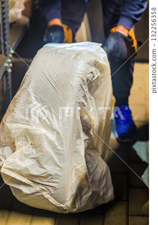 Worker Packing Car Tire into Plastic Bag for Seasonal Storage 132256358