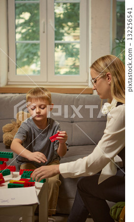 Psychologist observing boy building toy blocks during therapy focused on creativity 132256541