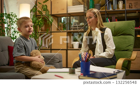Boy holding teddy bear during counseling conversation with female psychologist Boy holding teddy bear during counseling conversation with female psychologist 132256548