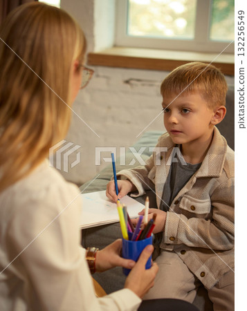 Boy drawing during art therapy session with psychologist supporting creative expression Boy drawing during art therapy session with psychologist supporting creative expression 132256549