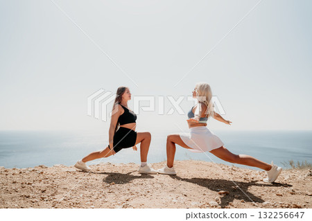 Two Women Stretching on a Cliffside with Ocean View Two Women Stretching on a Cliffside with Ocean View 132256647