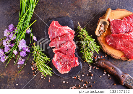 A piece of beef with spices and rosemary on a dark background 132257132