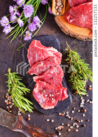 A piece of beef with spices and rosemary on a dark background 132257133