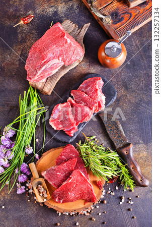 A piece of beef with spices and rosemary on a dark background 132257134