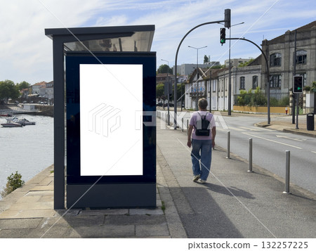 Billboard stands on city street. Modern blank vertical panel offers clean white display space at bus Billboard stands on city street. Modern blank vertical panel offers clean white display space at bus 132257225