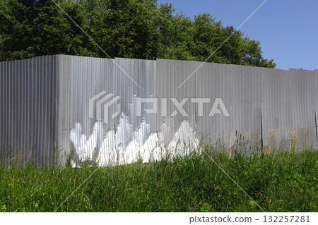 Fence structure in rural field. Metal corrugated barrier with vertical galvanized sheet texture 132257281