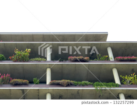 Greenery adorns modern residential facade. Colorful balcony planters create vertical garden with 132257299