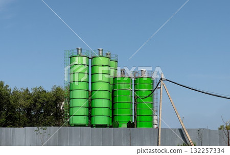 Silos towers, industrial landscape. Concrete and metal vertical towers store raw cement material at Silos towers, industrial landscape. Concrete and metal vertical towers store raw cement material at 132257334