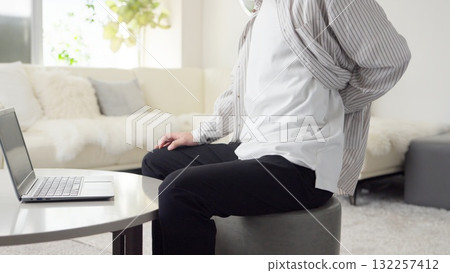 Asian man suffering from back pain while working on a computer 132257412