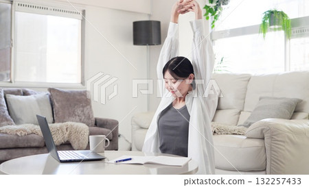 Asian woman stretching while studying Asian woman stretching while studying 132257433