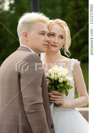 Young couple poses together after ceremony in a lush outdoor setting Young couple poses together after ceremony in a lush outdoor setting 132257660