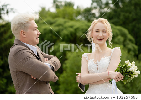 Joyful couple celebrates wedding outdoors with smiles and flowers Joyful couple celebrates wedding outdoors with smiles and flowers 132257663